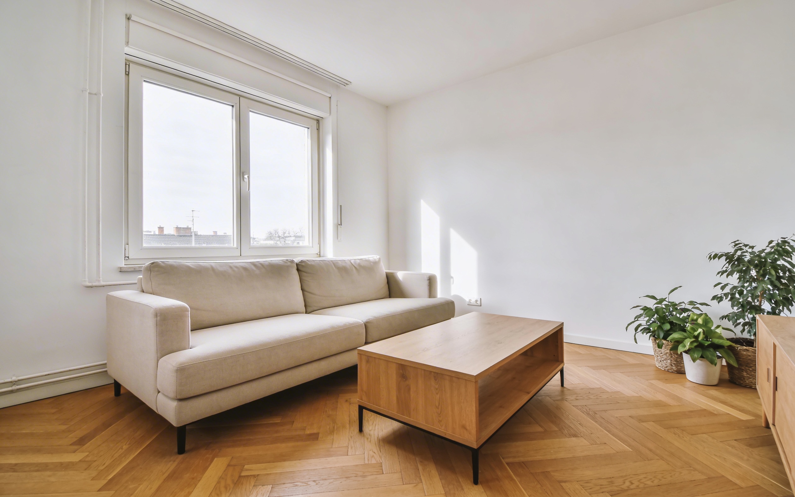Moderan svetao dnevni boravak u apartmanu stan na dan sa bež sofom, drvenim stolom i velikim prozorom